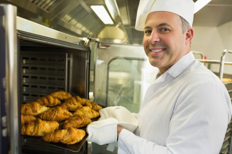 Baker taking out bread from oven