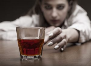 woman reaching for glass with alcohol
