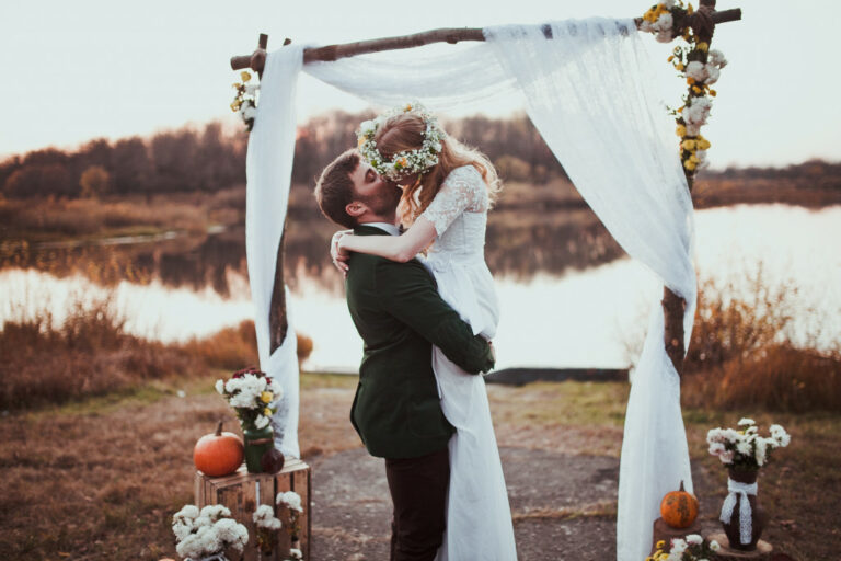 A bride and groom kissing outdoors on autumn