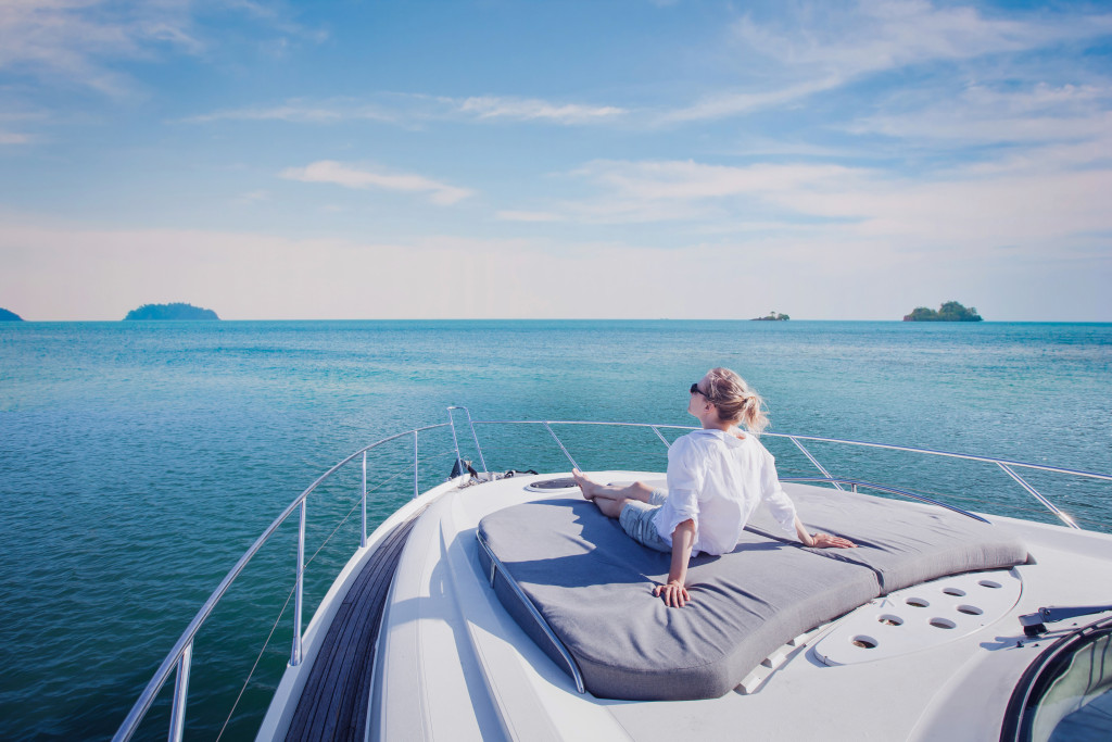 Young woman sitting on the bow of a luxurious yacht while traveling across an archipelago.