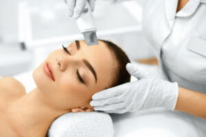 woman with eyes closed as aesthetician uses tool for microdermabrasion
