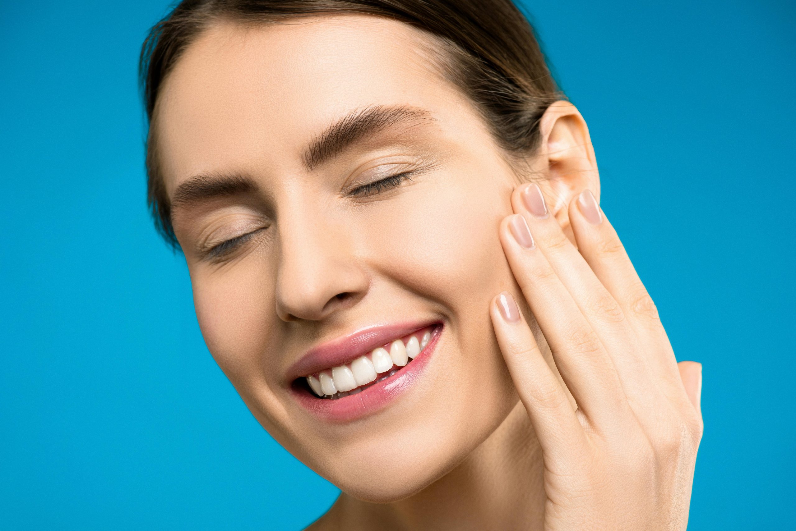 smiling woman touching her blemish-free face