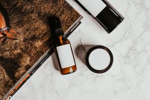 a bottle of retinol serum and a jar of moisturizer placed on a white marble surface